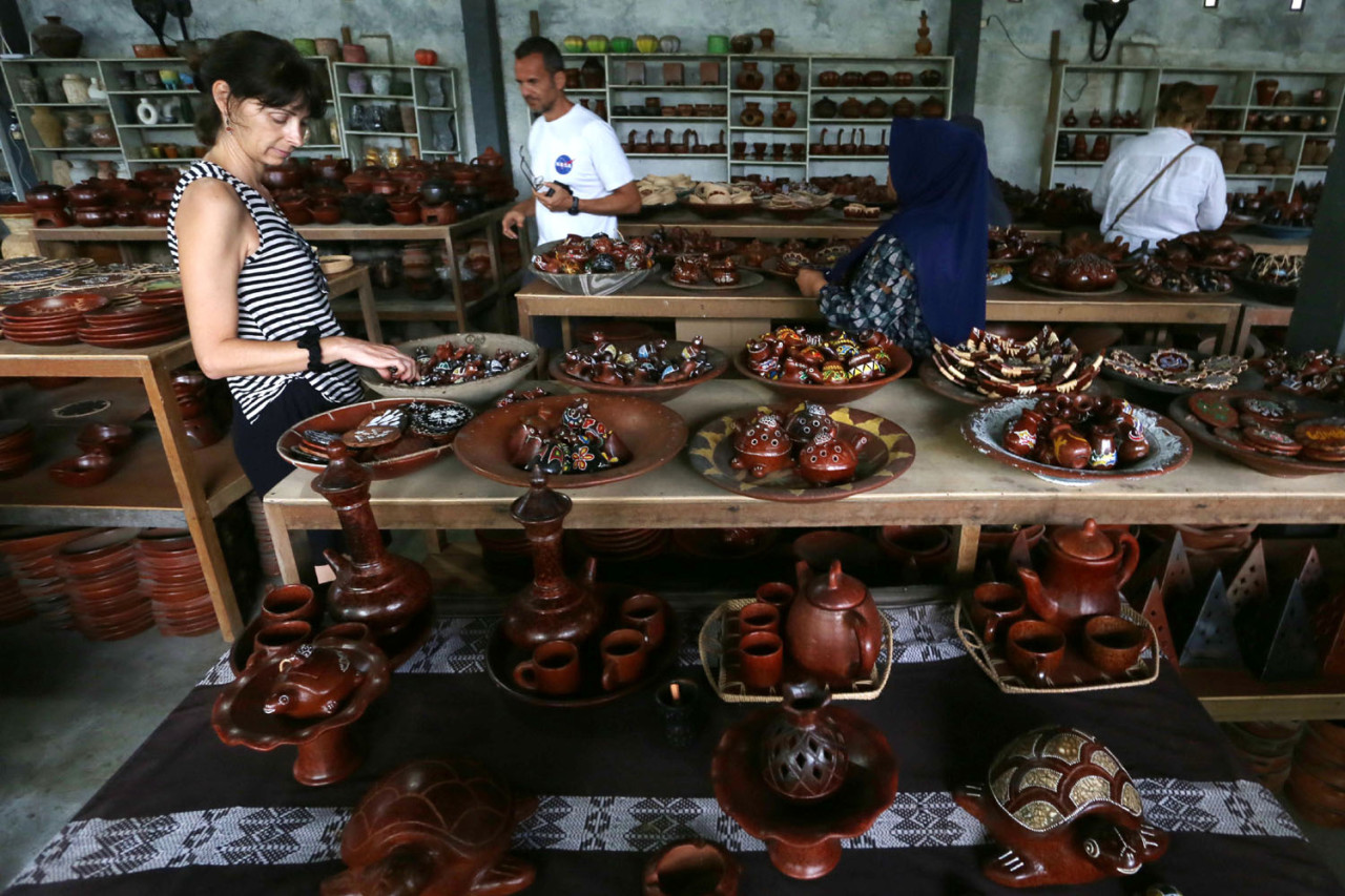 Turis mancanegara memilih kerajinan gerabah tradisional Banyumulek, Lombok Barat, Sabtu (27/12/2025). Kerajinan khas Lombok ini menjadi salah satu daya pikat turis asing. (Foto: Ali Masduki/jatimnow.com)