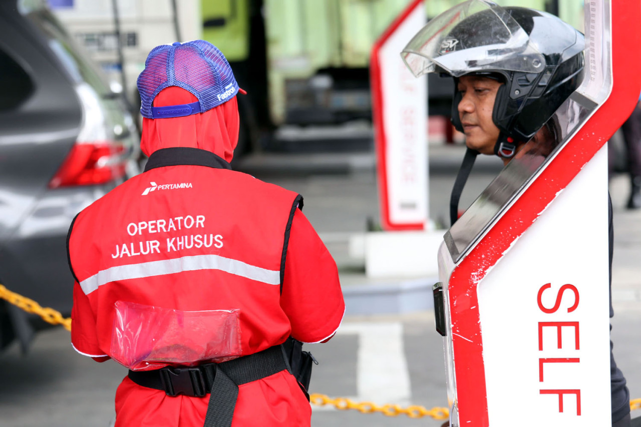 Operator jalur khusus berada di area layanan self-service SPBU COCO Jemursari, Surabaya, Rabu (24/12/2025). Meski konsumen mengisi BBM secara mandiri melalui sistem barcode dan dispenser, petugas tetap siaga untuk memastikan proses berjalan aman dan tepat. (Foto: Ali Masduki/jatimnow.com)