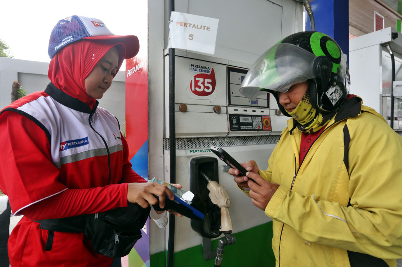 Petugas SPBU melayani proses pembayaran sebelum pengisian BBM mandiri di SPBU COCO Jemursari, Surabaya, Rabu (24/12/2025). Konsumen menunjukkan transaksi digital melalui aplikasi MyPertamina untuk mendapatkan struk berisi barcode sebagai langkah awal layanan self-service. Skema ini menjadi bagian dari transformasi layanan SPBU yang mengedepankan kecepatan, ketertiban, dan efisiensi melalui dukungan digitalisasi. (Foto: Ali Masduki/jatimnow.com)