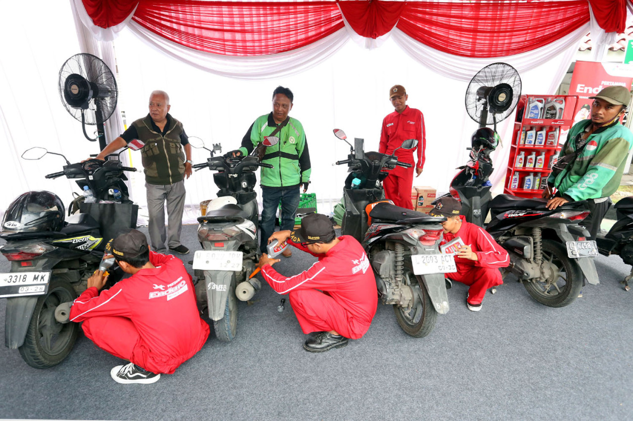 Pengemudi ojek online mengikuti layanan ganti oli gratis yang digelar Pertamina Patra Niaga melalui Enduro Entrepreneurship Program di SPBU COCO Jemursari, Surabaya, Rabu (24/12/2025). (Foto: Ali Masduki/jatimnow.com)
