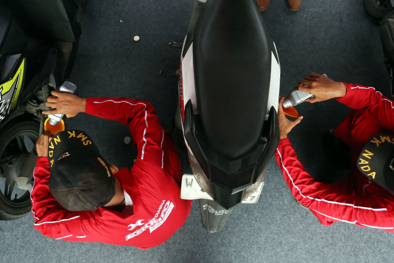 Petugas melakukan penggantian oli sepeda motor milik pengemudi ojek online dalam program servis oli gratis yang digelar Pertamina Patra Niaga melalui Enduro Entrepreneurship Program di SPBU COCO Jemursari, Surabaya, Rabu (24/12/2025). Program ini menjadi bentuk apresiasi sekaligus dukungan bagi para driver ojol agar kendaraan tetap prima dan operasional harian lebih ringan. (Foto: Ali Masduki/jatimnow.com)