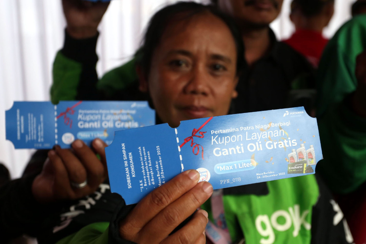 Seorang pengemudi ojek online menunjukkan kupon layanan ganti oli gratis yang dibagikan Pertamina Patra Niaga dalam program Enduro Entrepreneurship Program di SPBU COCO Jemursari, Surabaya, Rabu (24/12/2025). Kupon tersebut menjadi akses bagi para driver ojol untuk mendapatkan servis oli sebagai bentuk apresiasi dan dukungan terhadap kesejahteraan mereka. (Foto: Ali Masduki/jatimnow.com)