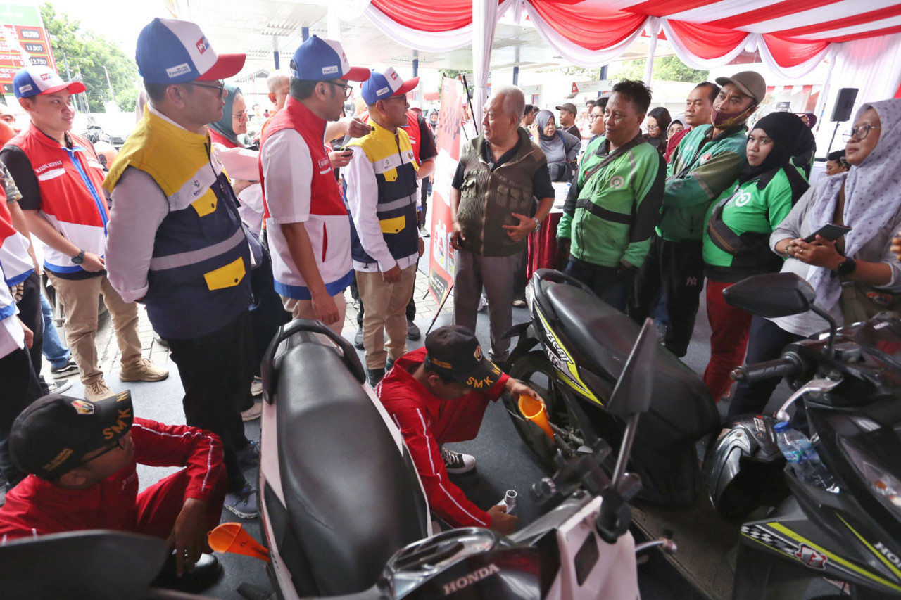 Petugas melakukan servis oli gratis pada sepeda motor pengemudi ojek online saat program Enduro Entrepreneurship Program yang digelar Pertamina Patra Niaga di SPBU COCO Jemursari, Surabaya, Rabu (24/12/2025). Sejumlah manajemen Pertamina Patra Niaga turut berdialog dengan para driver ojol sebagai bentuk apresiasi dan dukungan langsung terhadap para mitra penggerak ekonomi jalanan. (Foto: Ali Masduki/jatimnow.com)