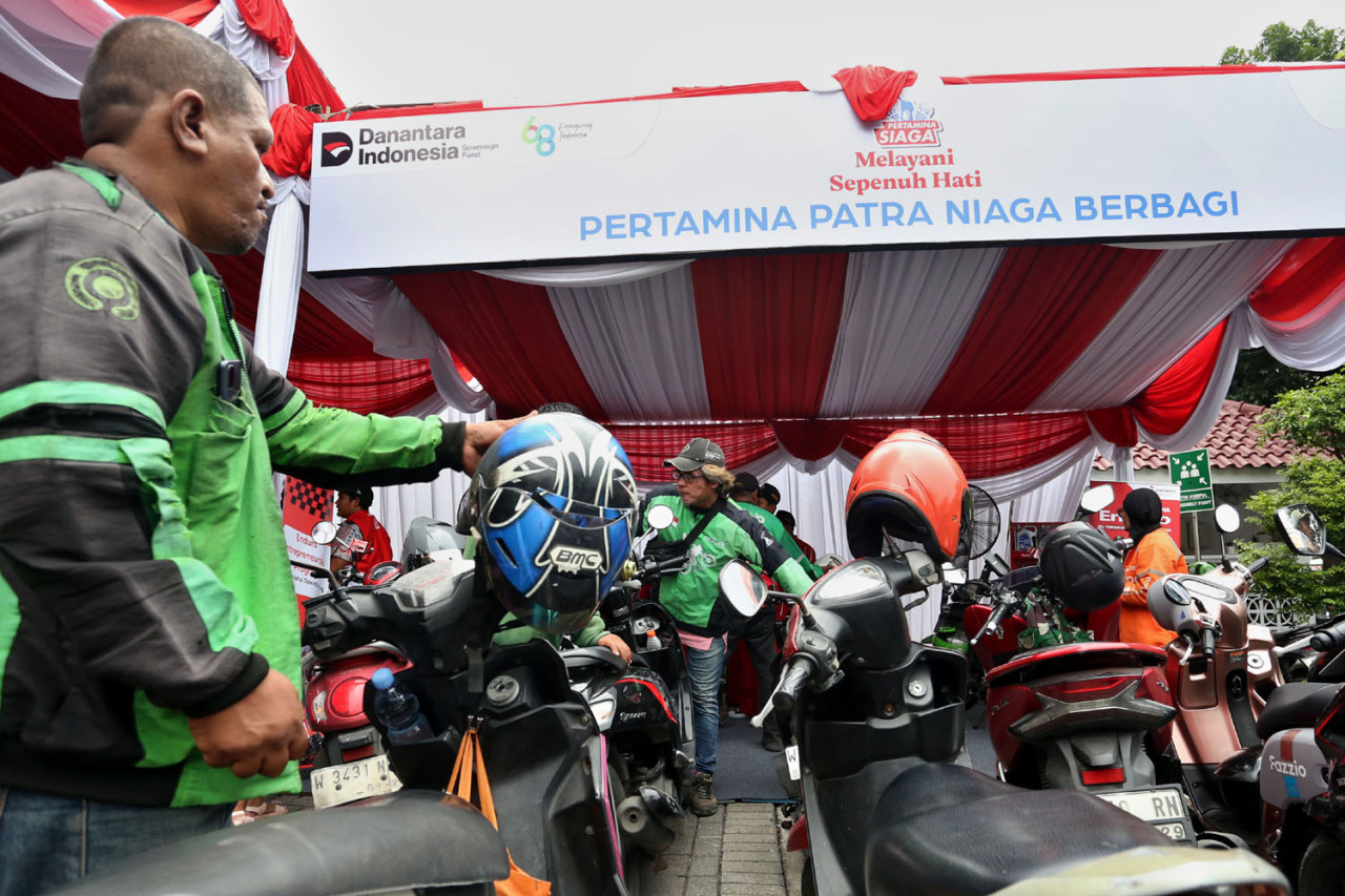 Pengemudi ojek online memadati area layanan servis oli gratis yang digelar Pertamina Patra Niaga melalui Enduro Entrepreneurship Program di SPBU COCO Jemursari, Surabaya, Rabu (24/12/2025). Program bertajuk Pertamina Patra Niaga Berbagi ini menjadi bentuk kepedulian perusahaan dalam mendukung kelancaran mobilitas dan keberlanjutan ekonomi para driver ojol. (Foto: Ali Masduki/jatimnow.com)