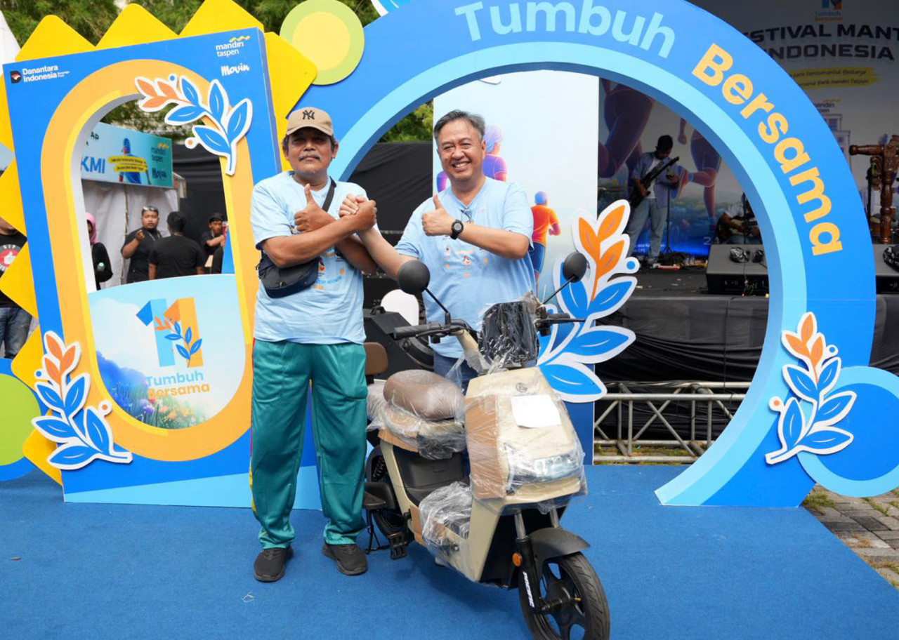 Direktur Utama Bank Mandiri Taspen, Panji irawan (kanan), menyerahkan hadiah sepeda listrik kepada salah satu nasabah, dalam perayaan HUT ke-11 Bank Mandiri Taspen di Surabaya. (Foto: Bank Mandiri Taspen/jatimnow.com)