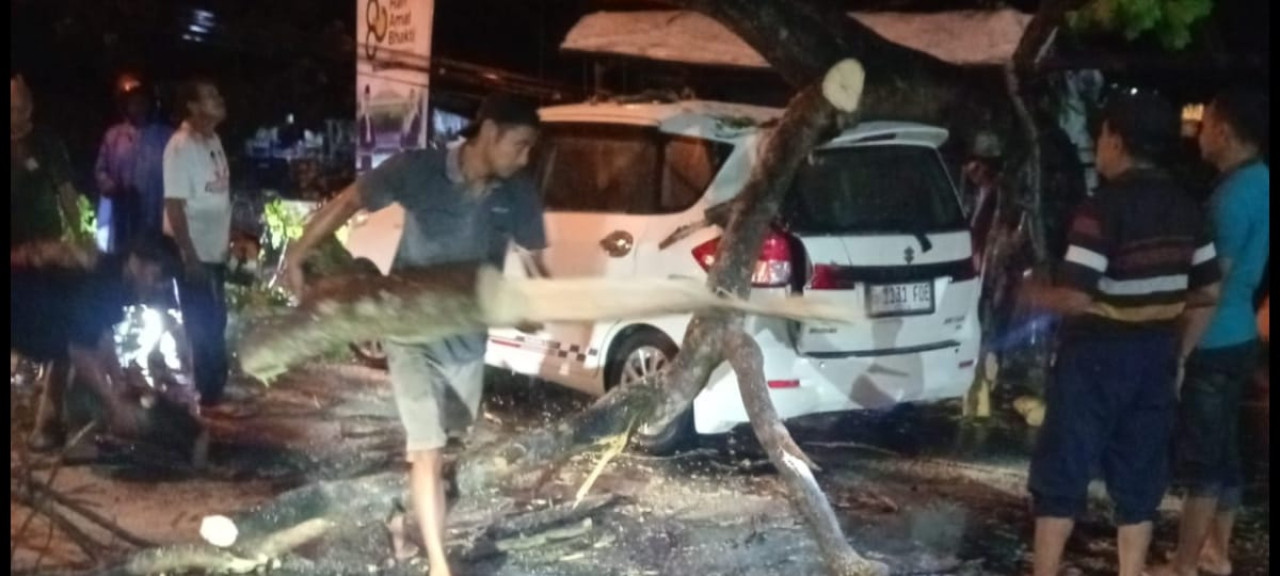 Foto: Warga mengevakuasi pohon yang menimpa mobil di Tulungagung. (Polsek Bandung/jatimnow.com)