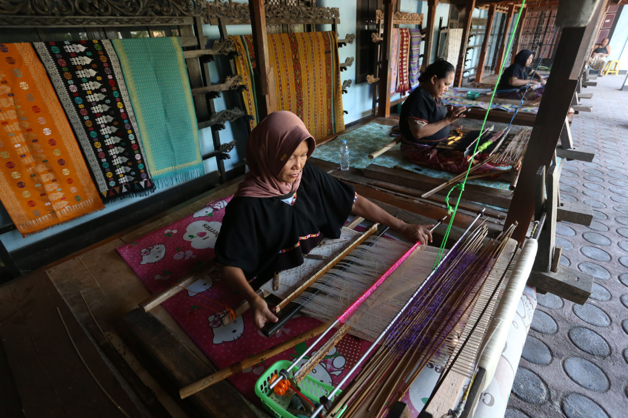 Perempuan-perempuan penenun Desa Sukarara, Lombok Tengah, dengan telaten menganyam benang demi benang menjadi kain songket tradisional khas Sasak, menjaga warisan budaya agar tetap hidup di tengah arus modernisasi. (Foto: Ali Masduki/jatimnow.com)
