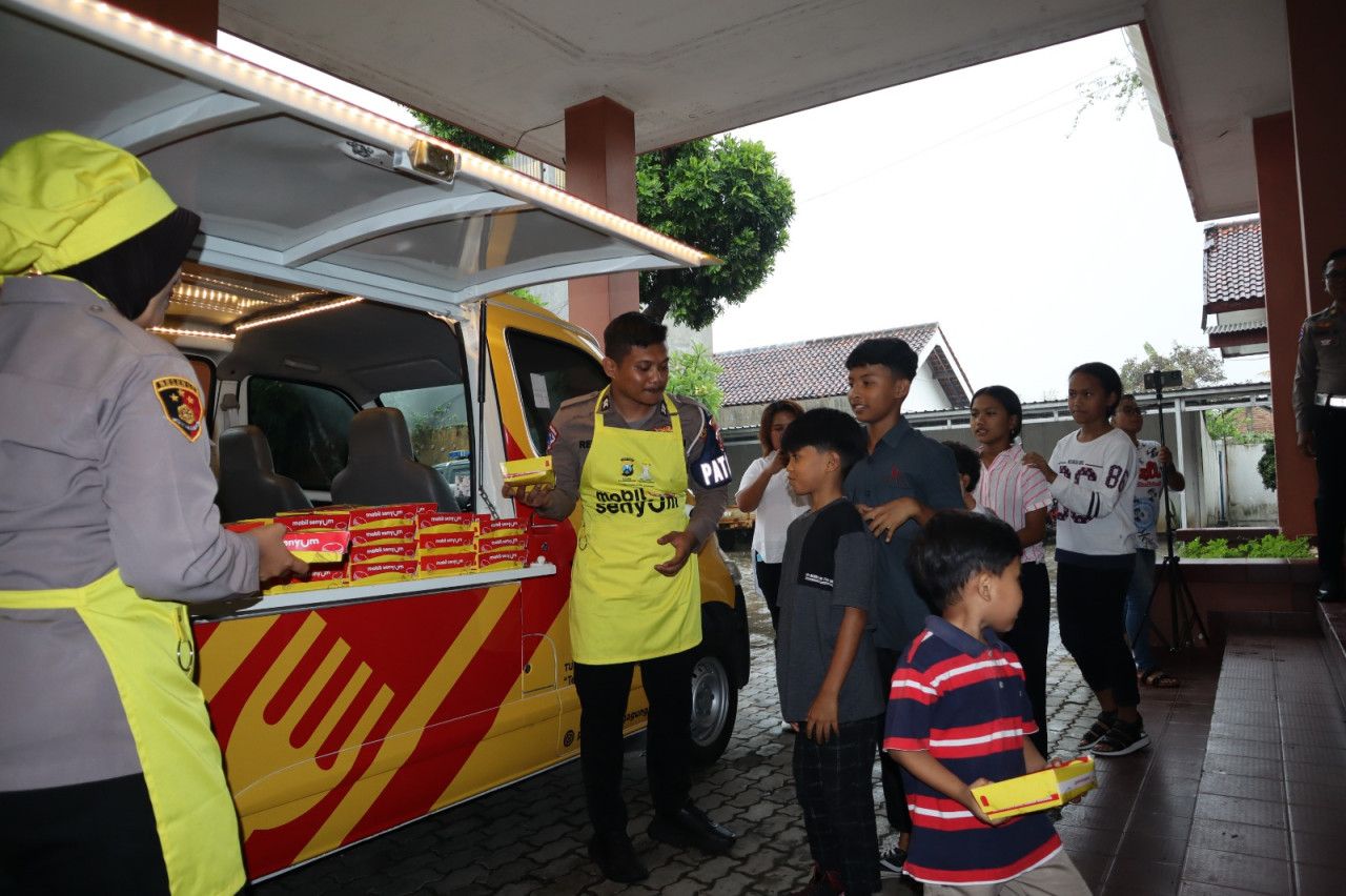 Foto: Petugas membagikan paket makanan program mobil senyum si kuning. (Polres Tulungagung/jatimnow.com)