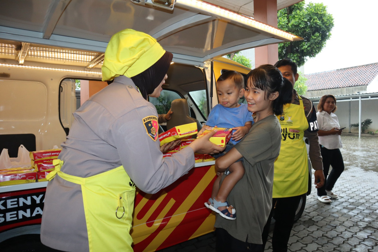 Foto: Petugas membagikan paket makanan dari progam mobil senyum si kuning. (Polres Tulungagung/jatimnow.com)