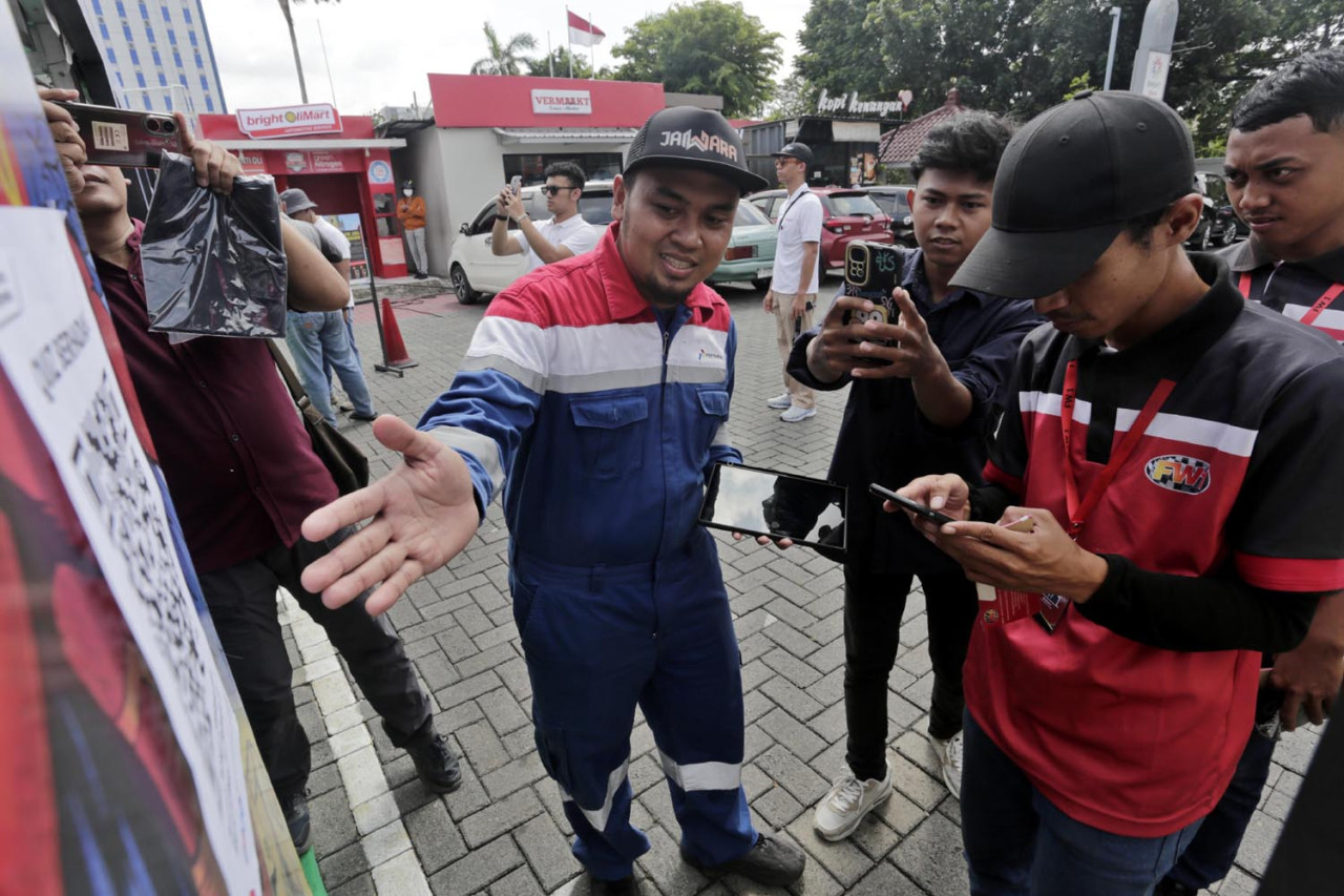 Petugas mengarahkan para pengendara memindai barcode untuk membuka tautan ketika akan mengikuti kuis Keselamatan dan Kesehatan Kerja (K3) di SPBU Coco Jemursari, Surabaya, Kamis (05/2/2026). Momen bulan K3 Nasional 2026 dimanfaatkan tim Pertamina Patra Niaga Regional Jatimbalinus untuk menyapa langsung konsumen. (Foto: Ali Masduki/jatimnow.com)