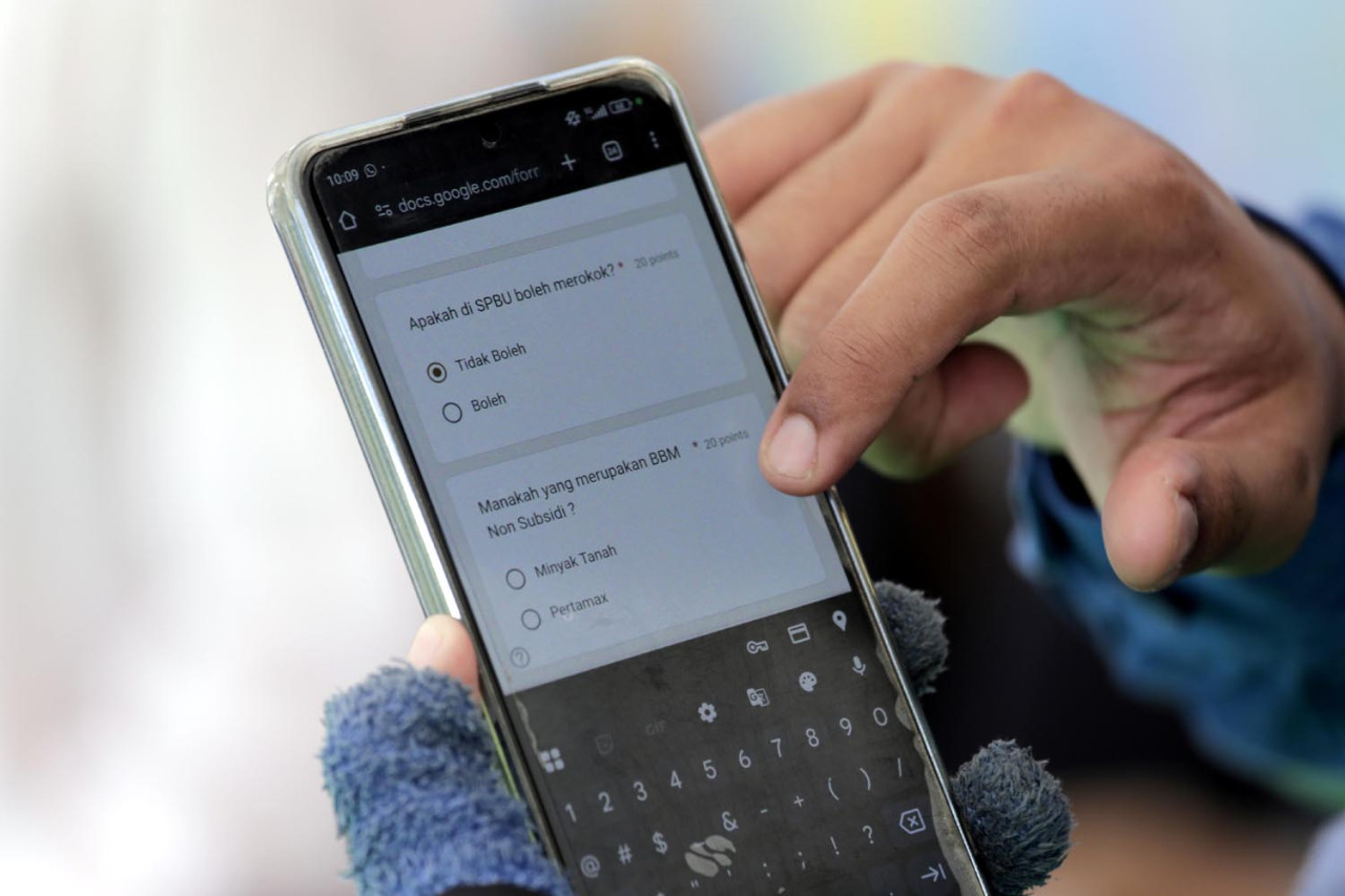 Pengendara berusaha menjawab kuis seputar Keselamatan dan Kesehatan Kerja (K3) dan produk Pertamina, ketika mengisi BBM di SPBU Coco Jemursari, Surabaya, Kamis (05/2/2026). Kuis tersebut guna meliterasi masyarakat tentang keselamatan dengan cara menyenangkan. (Foto: Ali Masduki/jatimnow.com)