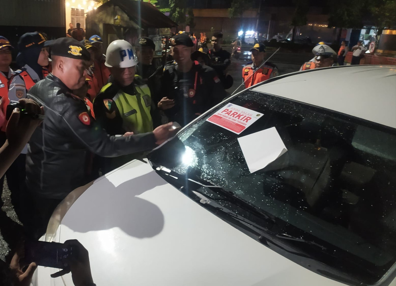 Petugas menempel stiker sebagai sanksi untuk kendaraan yang parkir sembarangan. (Foto: Sugianto/jatimnow.com)