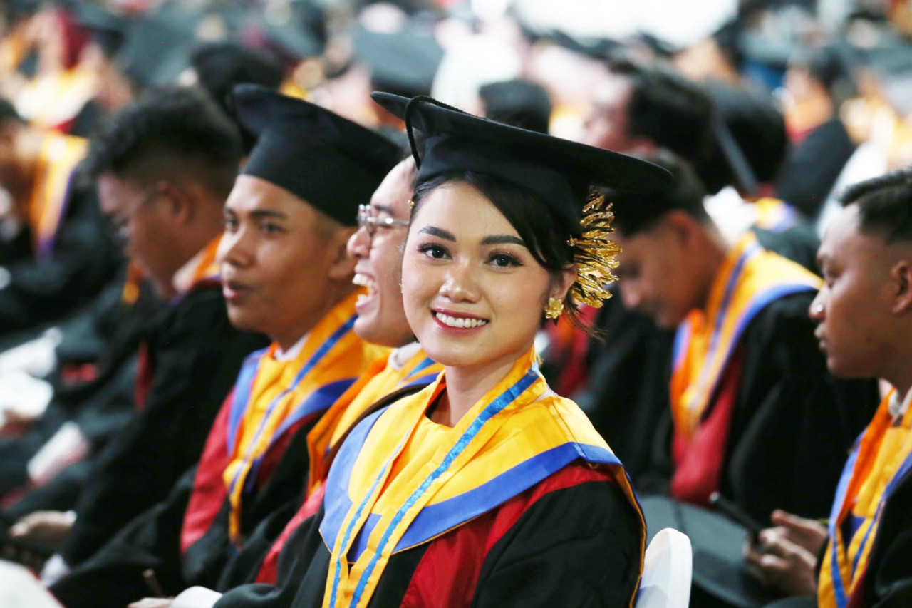 Ni Kadek Ayu Wardani, melontarkan senyum ketika mengikuti prosesi Wisuda ke-132 Untag Surabaya pada Minggu (15/2/2026). (Foto: Ali Masduki/jatimnow.com)