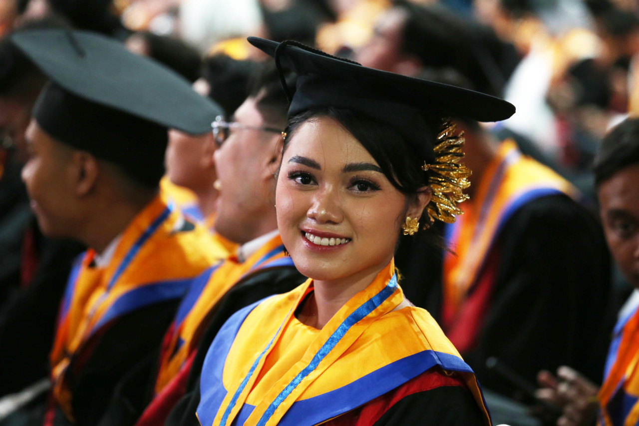 Ketua DPC GMNI Surabaya Raya periode 2025–2027, Ni Kadek Ayu Wardani, melontarkan senyum ketika mengikuti prosesi Wisuda ke-132 Untag Surabaya pada Minggu (15/2/2026). Sebagai pemimpin organisasi pergerakan mahasiswa, Kadek berhasil menuntaskan akademik dan mematahkan mitos jika aktivis kerap gagal dalam perkuliahan. (Foto: Ali Masduki/jatimnow.com)