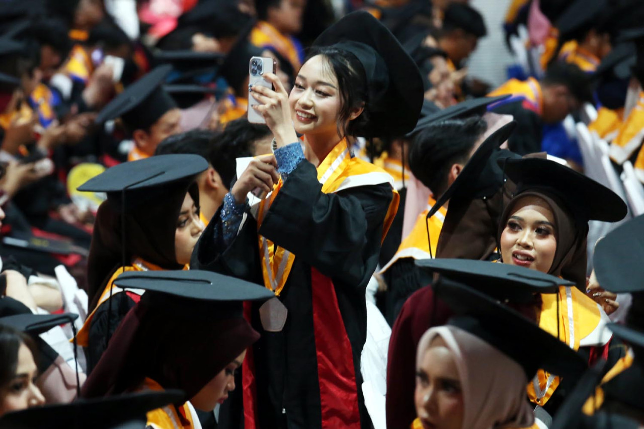 Seorang wisudawati mengabadikan momen kebahagiaan ketika mengikuti prosesi Wisuda ke-132 Untag Surabaya pada Minggu (15/2/2026). Lulusan Untag Surabaya diharapkan tidak hanya sukses secara individu, tetapi juga mampu menghadirkan solusi nyata bagi persoalan masyarakat serta berkontribusi dalam perkembangan ilmu pengetahuan dan peradaban dunia. (Foto: Ali Masduki/jatimnow.com)