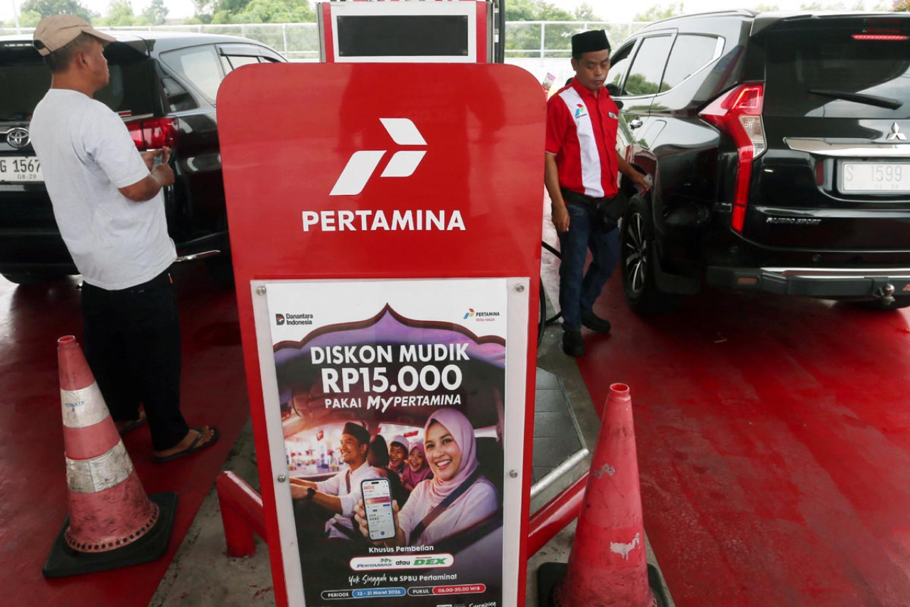 Pengendara mengisi bahan bakar di SPBU dengan latar promosi diskon mudik dari Pertamina yang menawarkan potongan hingga Rp15.000 bagi transaksi melalui aplikasi MyPertamina selama periode arus mudik Lebaran 2026. Program tersebut ditujukan untuk mempercepat layanan pengisian dan mengurangi antrean kendaraan di SPBU. (Foto: Ali Masduki/JatimNow.com)