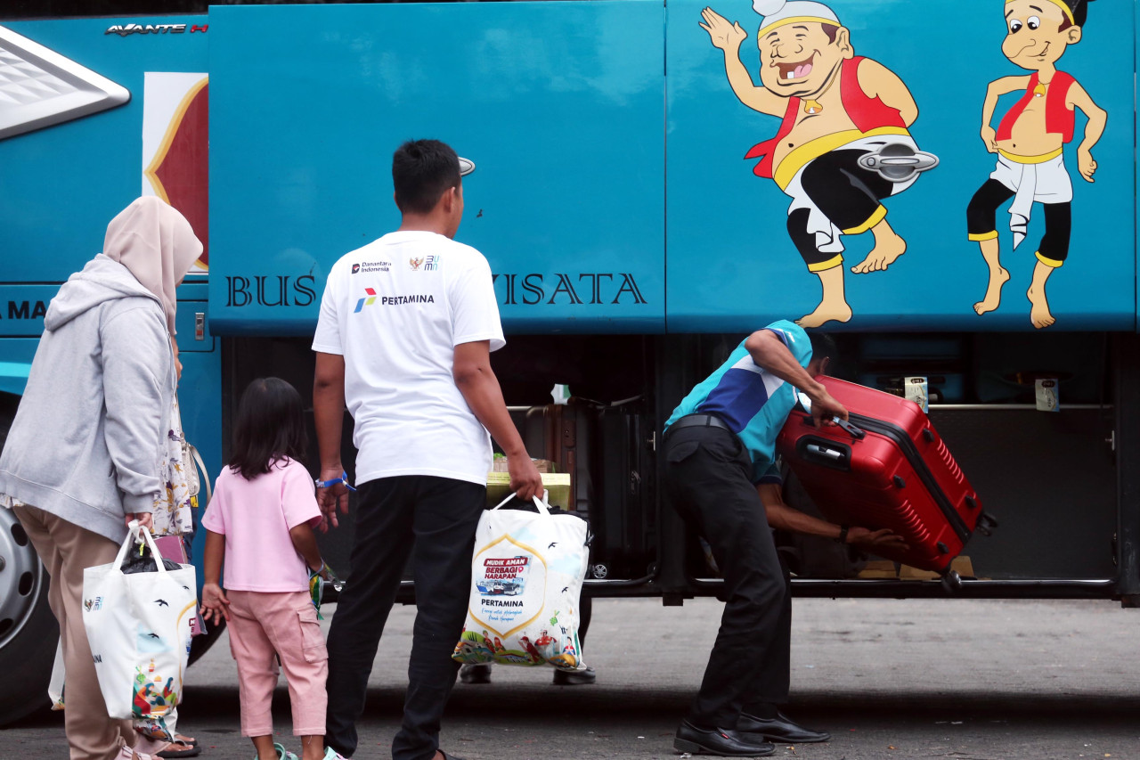Seorang petugas memasukkan koper ke bagasi bus saat peserta bersiap mengikuti program arus balik gratis yang digelar Pertamina di Surabaya, Sabtu (28/3/2026). Program ini membantu pemudik kembali ke Jakarta tanpa biaya, sekaligus menekan penggunaan kendaraan pribadi dan emisi selama periode arus balik Lebaran. (Foto: Ali Masduki/jatimnow.com).