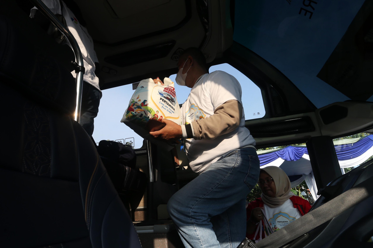 Pemudik membawa tas bingkisan saat menaiki bus program arus balik gratis yang digelar Pertamina di Surabaya, Sabtu (28/3/2026). Selain transportasi tanpa biaya, peserta juga mendapatkan perlengkapan perjalanan untuk menunjang kenyamanan selama perjalanan menuju Jakarta. (Foto: Ali Masduki/jatimnow.com).