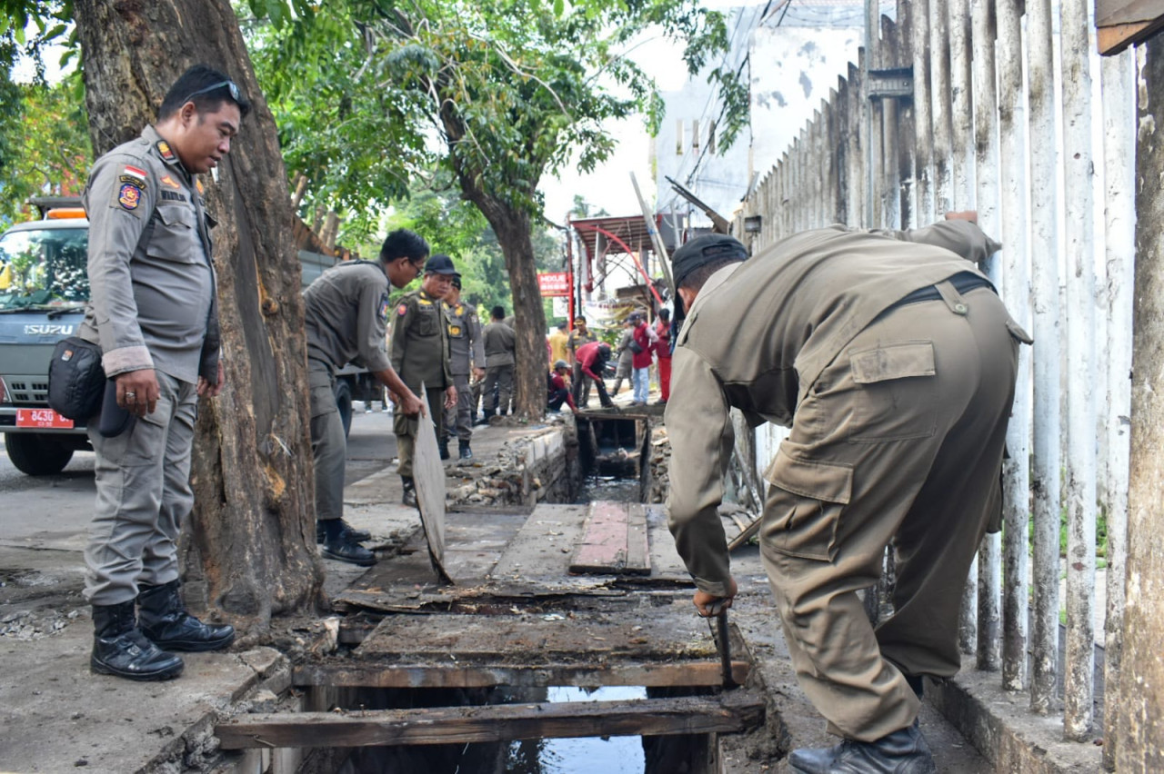Satpol PP Surabaya menertibkan PKL yang berjualan di atas saluran air kawasan Manukan. (Foto: Humas Pemkot Surabaya for jatimnow.com).