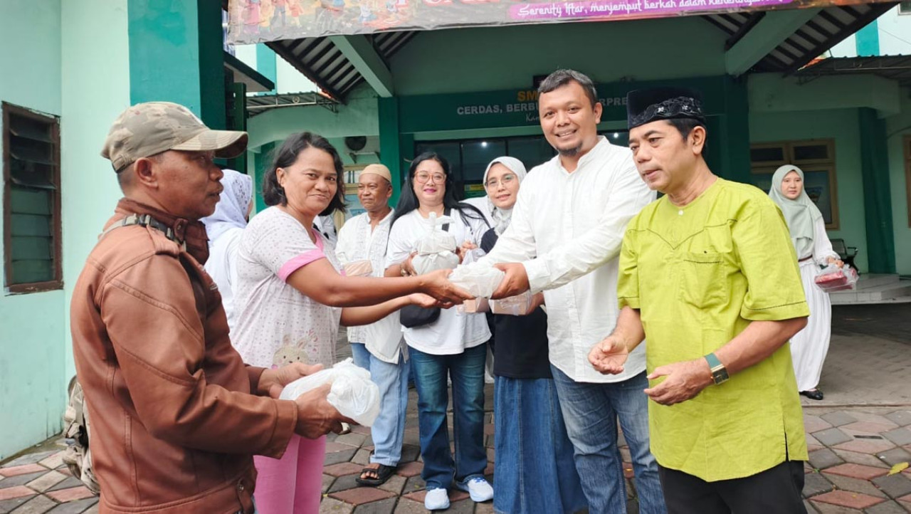 Perwakilan alumni menyerahkan paket takjil kepada warga dalam kegiatan berbagi Ramadan yang digelar Ikatan Keluarga Besar Alumni SMAN 14 Surabaya (IKA SMAPALAS) di halaman sekolah, Minggu (8/3/2026). (Foto: IKA SMAPALAS for JatimNow.com)