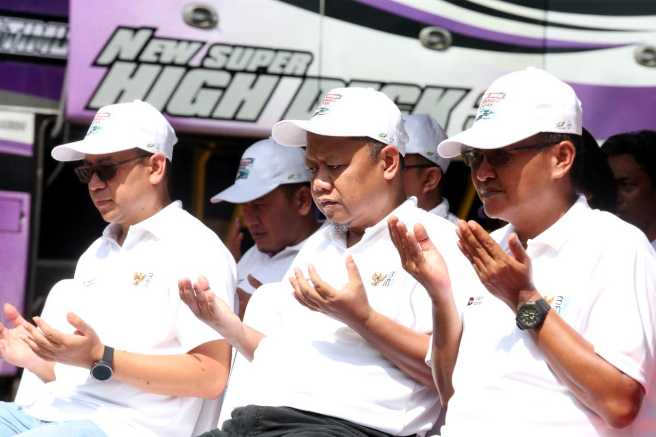 Manajemen PTPN I Regional 5 memimpin doa bersama saat melepas keberangkatan 600 peserta Mudik Gratis di Surabaya, Selasa (17/3). Program tahunan yang rutin digelar sejak 2017 ini mengerahkan 15 bus VIP untuk mengantar warga menuju berbagai kota di Jawa Tengah dan Jawa Timur guna mengurangi kepadatan kendaraan pribadi di jalan raya. (Foto: Ali Masduki/jatimnow.com)