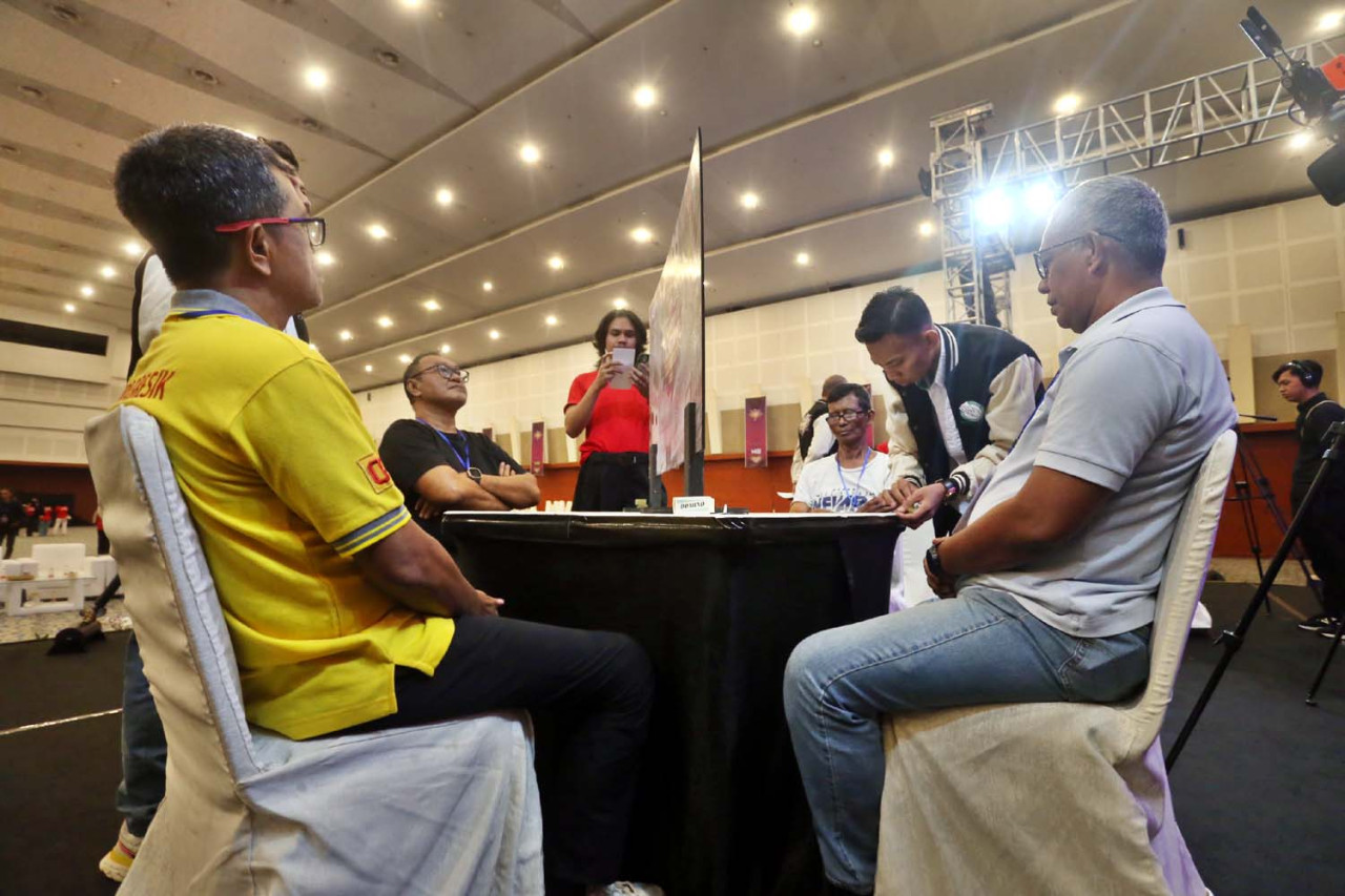 Juri memimpin dengan ketat jalannya final Surabaya Domino Tournament 2026 di Surabaya, di Grand City Convention Hall, Surabaya, Minggu (19/4/2026) malam. Turnamen yang diselenggarakan oleh HGI (Himpunan Game Indonesia) ini menerapkan sistem countdown (waktu pertandingan) yang ditampilkan secara digital di layar raksasa untuk memastikan intensitas dan kedisiplinan kompetisi. Penggunaan sekat meja tetap diberlakukan guna menjaga sportivitas dan integritas antar pemain selama pertandingan berlangsung. (Ali Masduki/jatimnow.com).