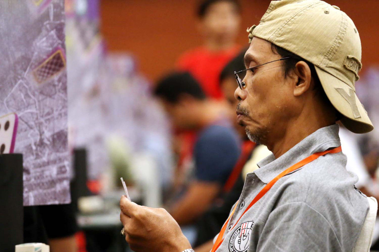 Ekspresi serius peserta saat menimbang langkah dalam Surabaya Domino Tournament 2026 di Grand City Convention Hall. Setiap keputusan di meja pertandingan menuntut ketepatan strategi dan konsentrasi tinggi di tengah persaingan ketat antar atlet. (Foto: Ali Masduki/jatimnow.com)