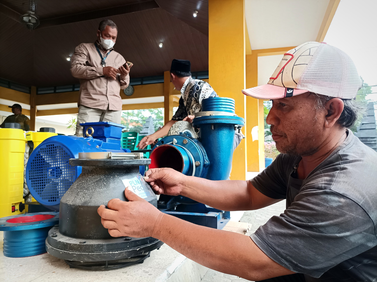 Salah satu anggota Gapoktan Desa Banjarsari, Kecamatan Cerme, Kabupaten Gresik, sedang menempel striker di mesin pompa eletrik bantuan dari PT PLN (Persero). (Foto: Sahlul Fahmi/jatimnow.com)