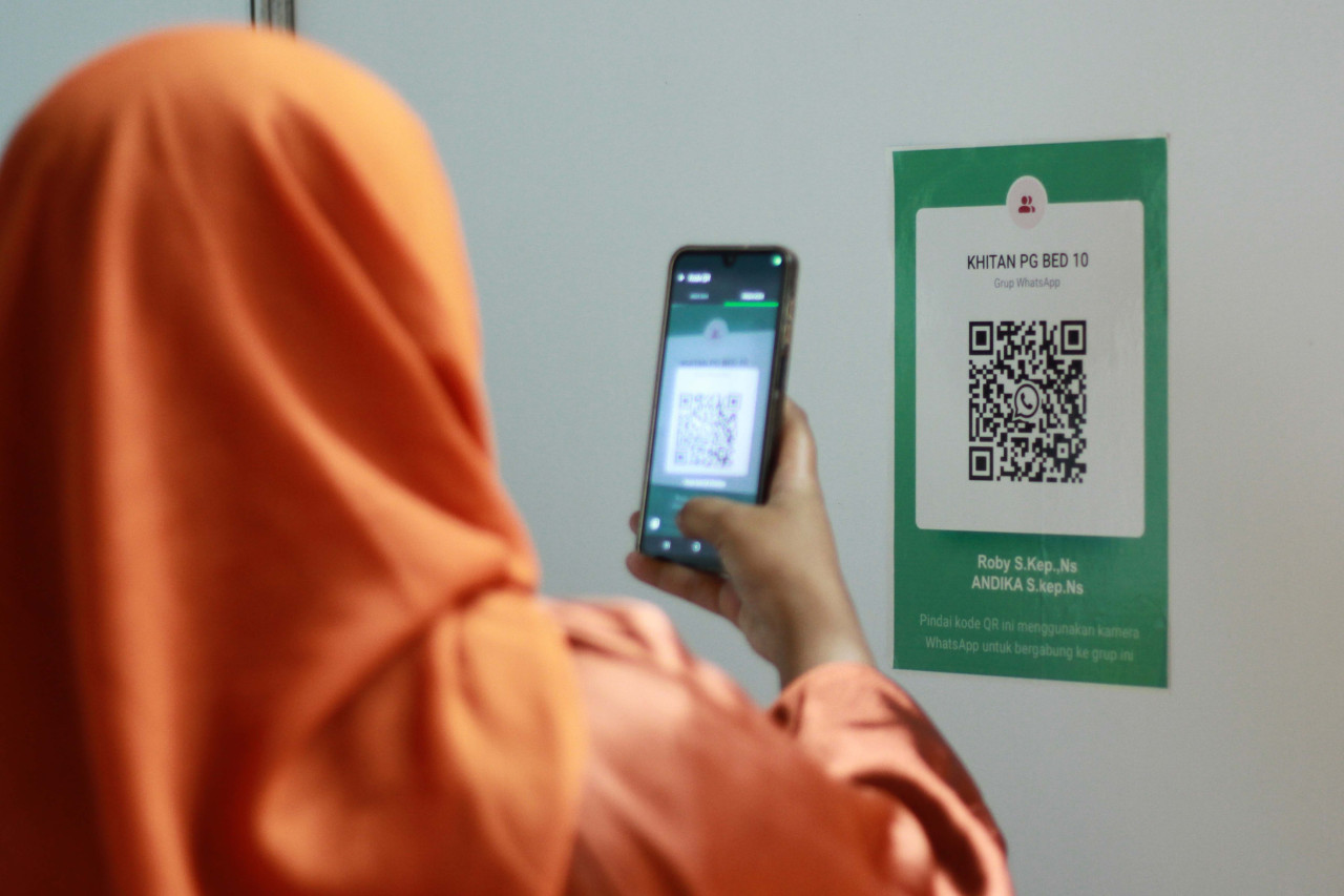 Salah satu orang tua peserta khitan gratis Petrokimia Gresik 2026 sedang scan barcode grup WA untuk pendampingan proses penyembuhan pasca khitan. (Foto: Sahlul Fahmi/jatimnow.com)