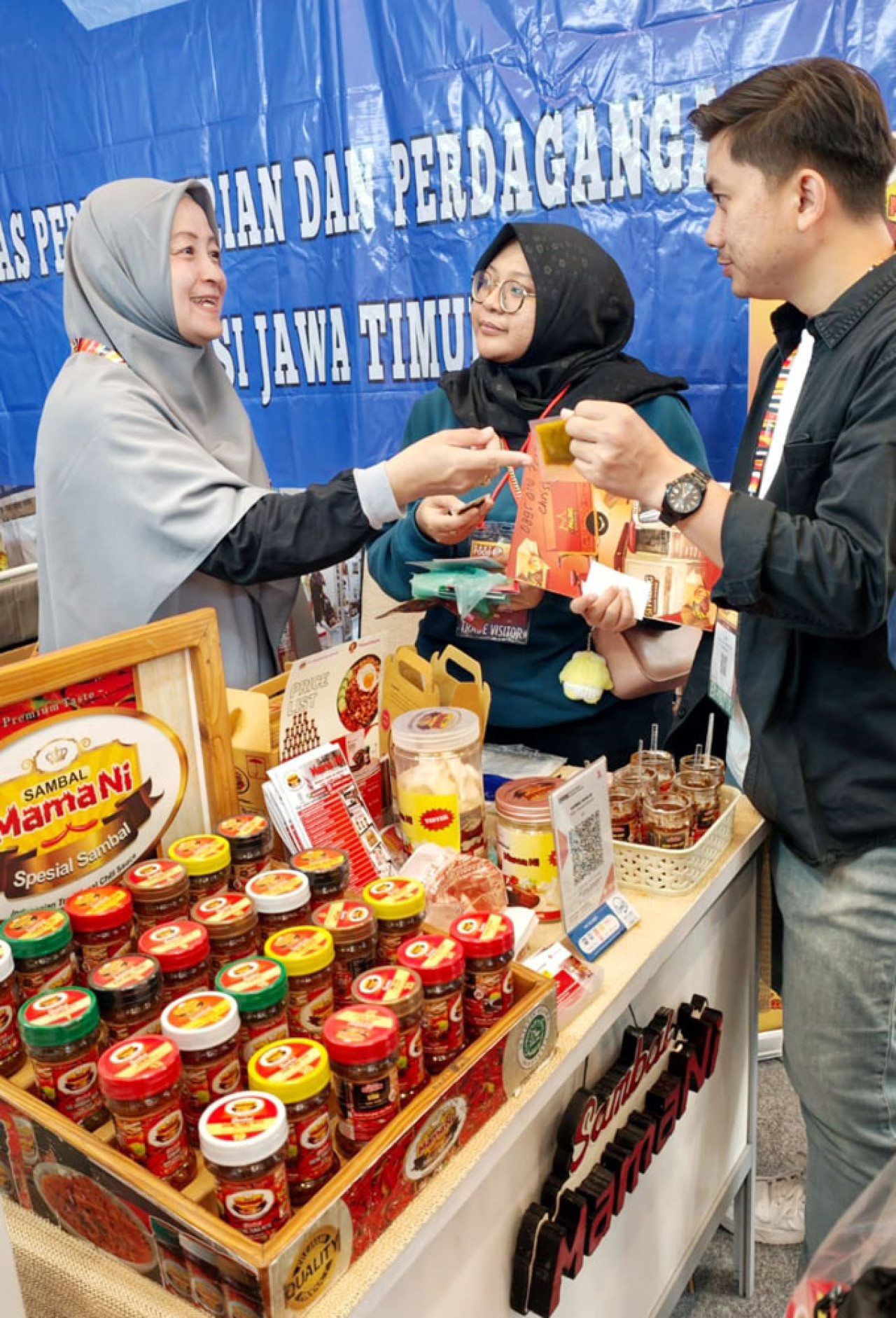 Heni Wardhani melayani pengunjung di stan Disperindag Jatim dalam gelaran IIFEX 2026 di Grand City Convention Hall Surabaya, Sabtu (20/6/2026) malam. (Foto: Ali Masduki/jatimnow.com)
