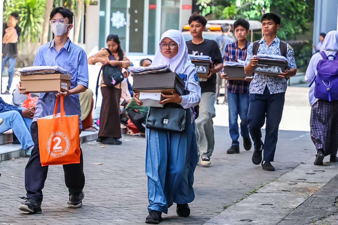 Sejumlah siswa membopong bantuan pendidikan dari Pemkot Surabaya