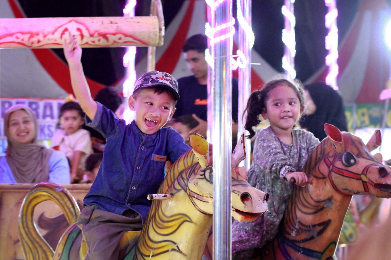 Keceriaan seorang anak saat menaiki komedi putar di PetroNite Fest 2026. (Foto: Sahlul Fahmi/jatimnow.com)