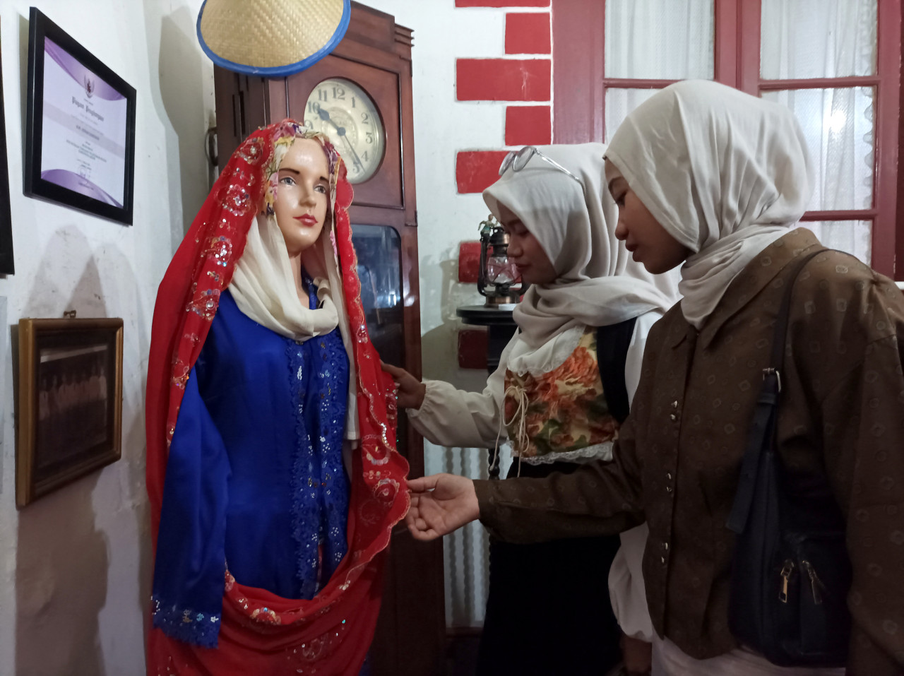 Pengunjung Festival "Menjadi Gresik" mengamati busana perempuan khas Gresik di masa lalu yang dipajang di salah satu rumah warga di Kampung Kemasan. (Foto: Sahlul Fahmi/jatimnow.com)