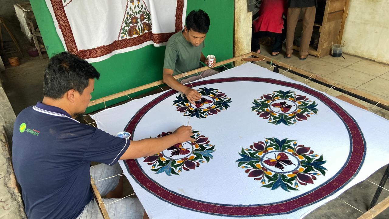 Ismanu bersama pekerja lain sedang mewarnai kain di salah satu sudut ruang kerja Batik Tulis Olive. Dia merupakan salah satu pekerja yang masih bertahan sejak awal Iwan membangun usaha ini. Menguasai seluruh tahapan batik, dia tak segan menularkan ilmunya kepada para pekerja muda.