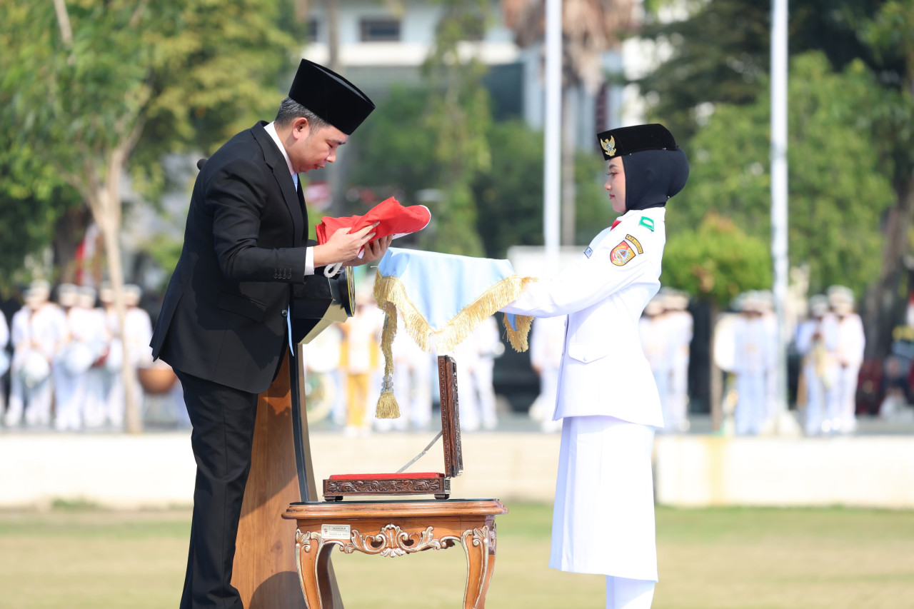 Bupati Jember, Muhammad Fawait menyerahkan Bendera Merah Putih yang akan dikibarkan. (Foto: Kominfo Jember for jatimnow.com)