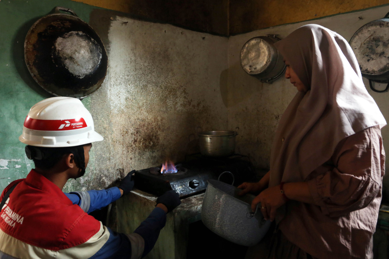Ernawati mengamati petugas PGN yang melakukan pengecekan kompor, Senin (03/8/2026). Ernawati merupakan salah satu dari ribuan pelanggan jaringan gas rumah tangga (Jargas) PGN di Kabupaten Lumajang, Jawa Timur. (Foto: Ali Masduki/jatimnow.com)