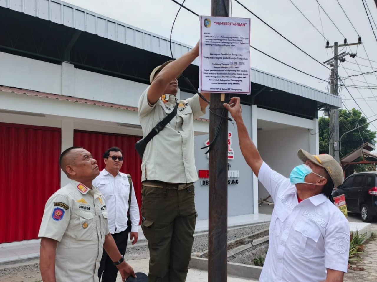 Petugas gabungan memasang papan peringatan di tiang FO ilegal. (Foto: Bramanta/jatimow.com)