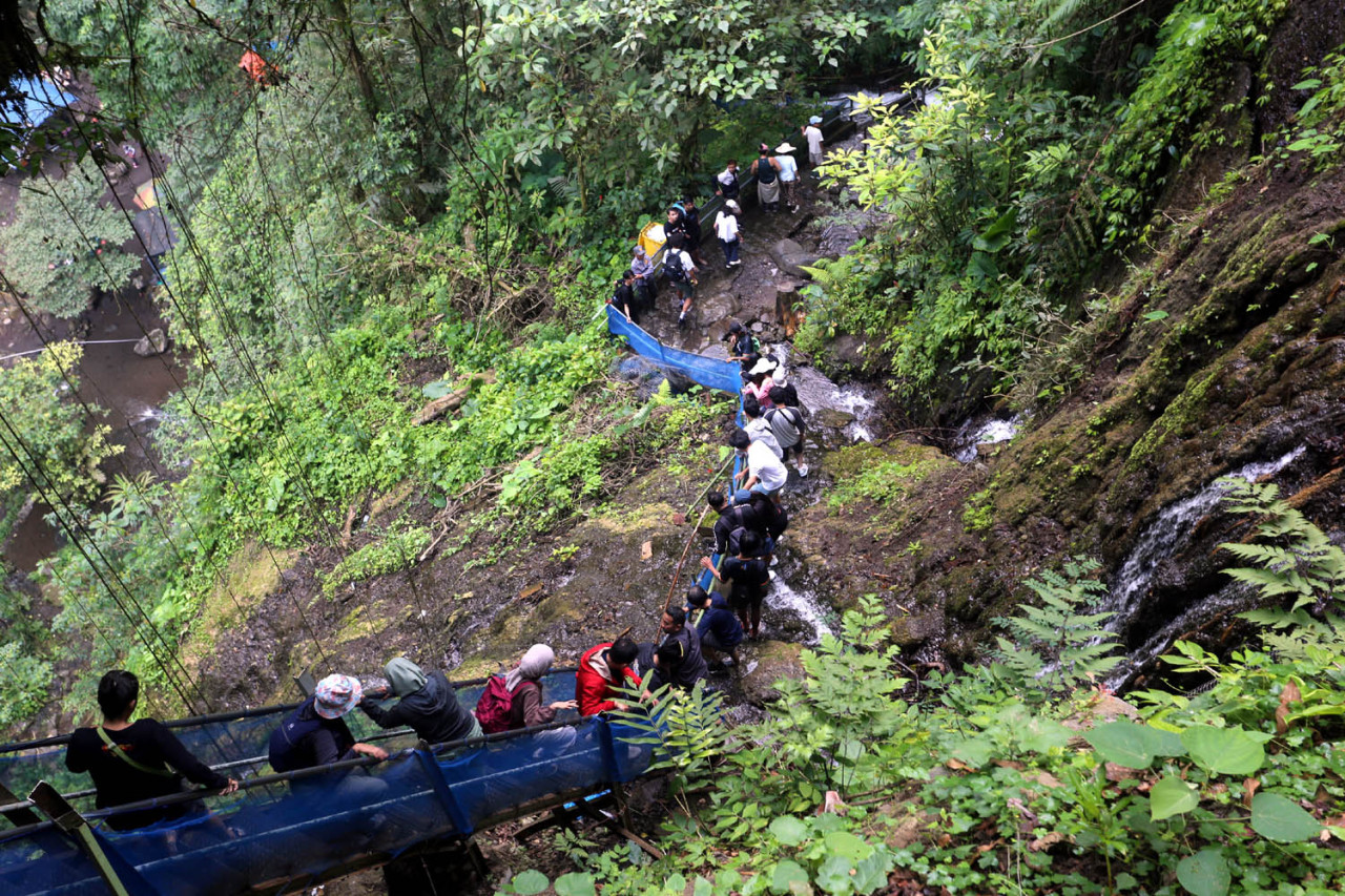 Kepadatan pengunjung di jalur pendakian yang ingin menikmati keindahan Air Terjun Tumpak Sewu. Wisatawan harus naik dan turun berjalan kaki sekitar 400 meter. (Foto: Ali Masduki/jatimnow.com)