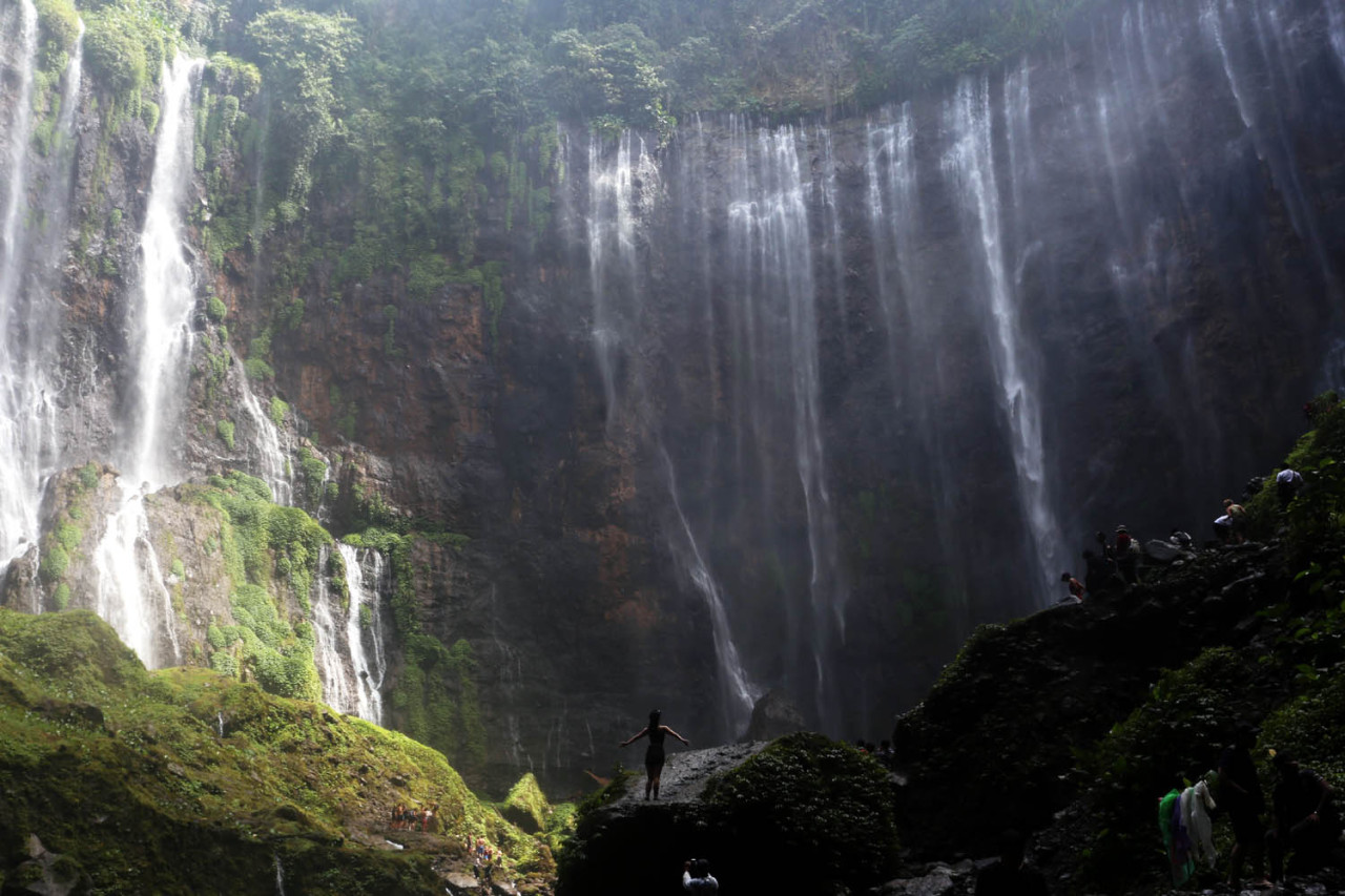 Seorang wisatawan berdiri menikmati keindahan Air Terjun Tumpak Sewu di Kabupaten Lumajang, Jawa Timur. Air terjun ini menjadi salah satu destinasi wisata alam unggulan di lereng Gunung Semeru. (Foto: Ali Masduki/jatimnow.com)