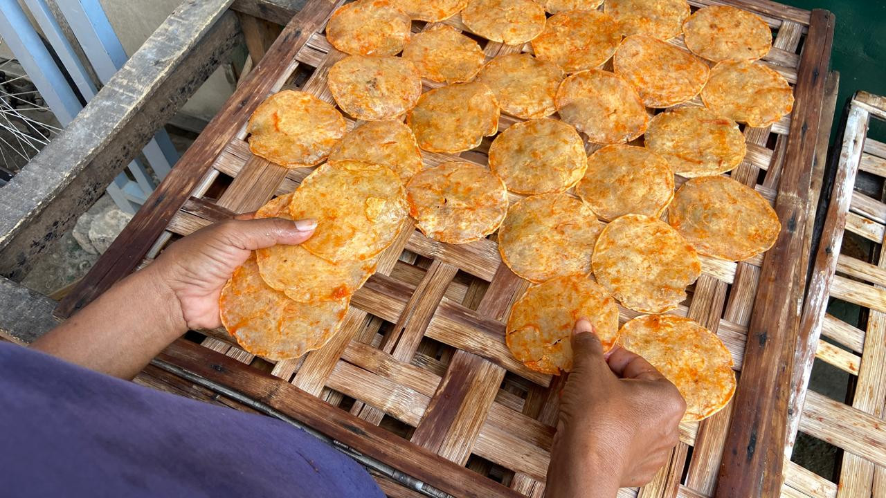 Sunaryo (53) menjemur emping rasa udang pedas manis di rumah produksi milik Maimunah di Kampung Emping Belinjo. Sejak 2020, ia bekerja pada usaha milik generasi kedua di kampung tersebut. (Foto: Yanuar Dedy/jatimnow.com)