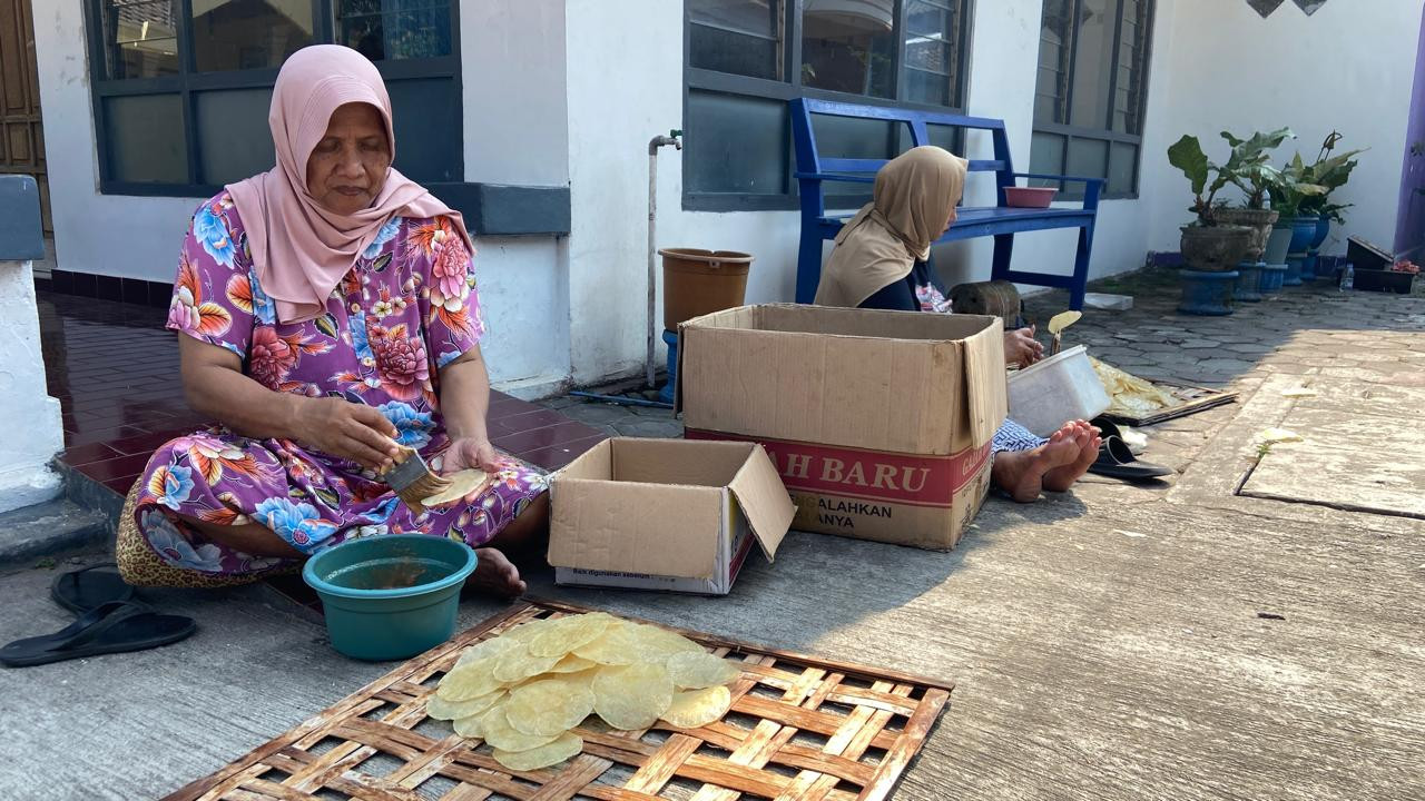 Maimunah (66) mengoleskan bumbu pada kepingan emping di kawasan Kampung Emping Belinjo, Kecamatan Pare, Kabupaten Kediri, Kamis (8/10/2026). Dia merupakan adik dari Mansyur. Keduanya sama-sama mewarisi usaha ayah mereka, Kasnan. (Foto: Yanuar Dedy/jatimnow.com)