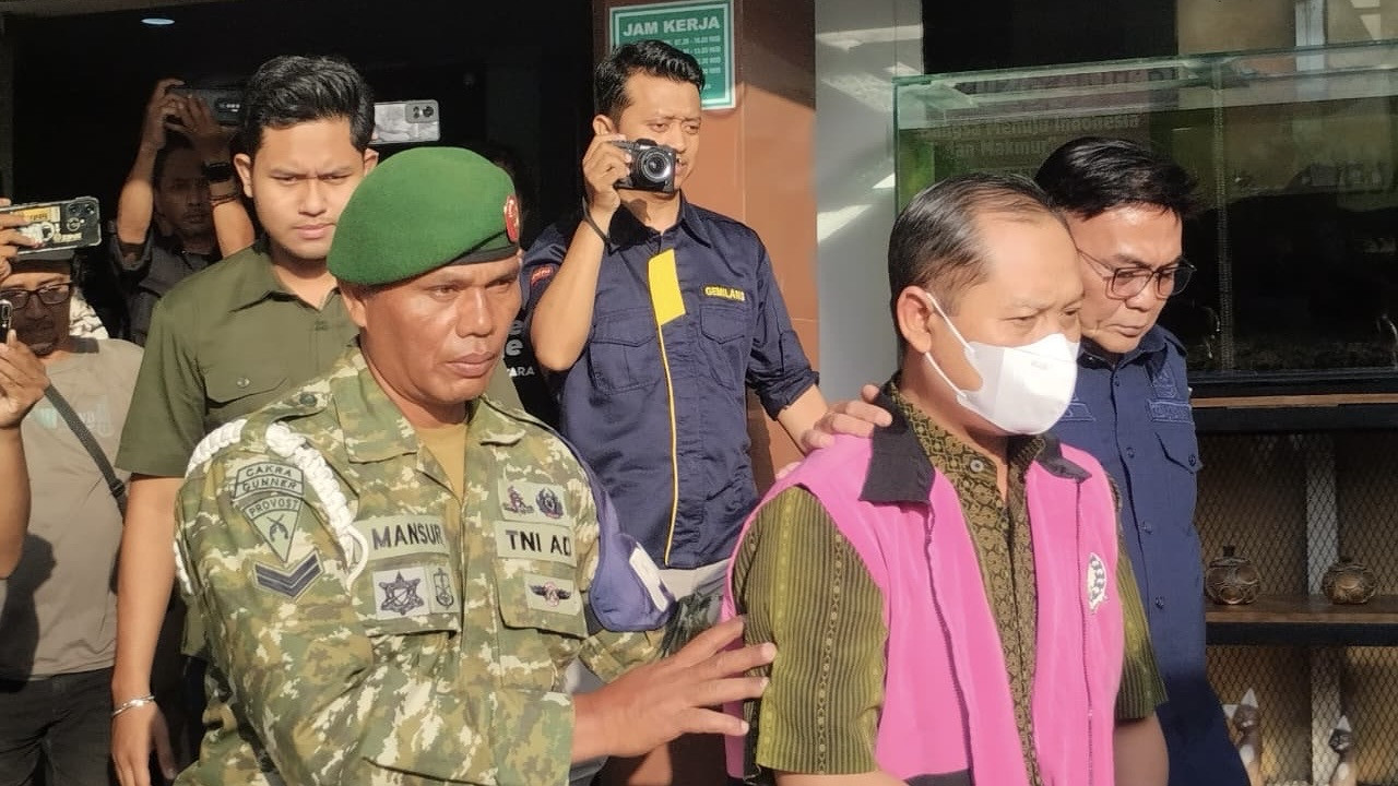 Mantan Sekwan DPRD Jember berinisial S saat digelandang menuju mobil tahanan. (Foto: Syakur/jatimnow.com)