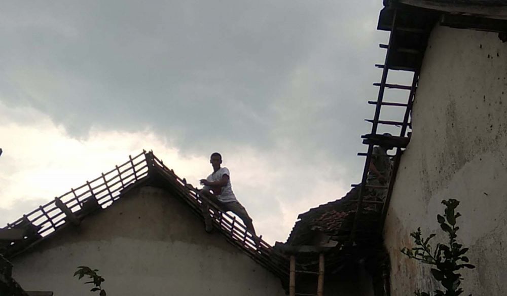 Warga memperbaiki atap rumahnya yang rusak akibat angin kencang