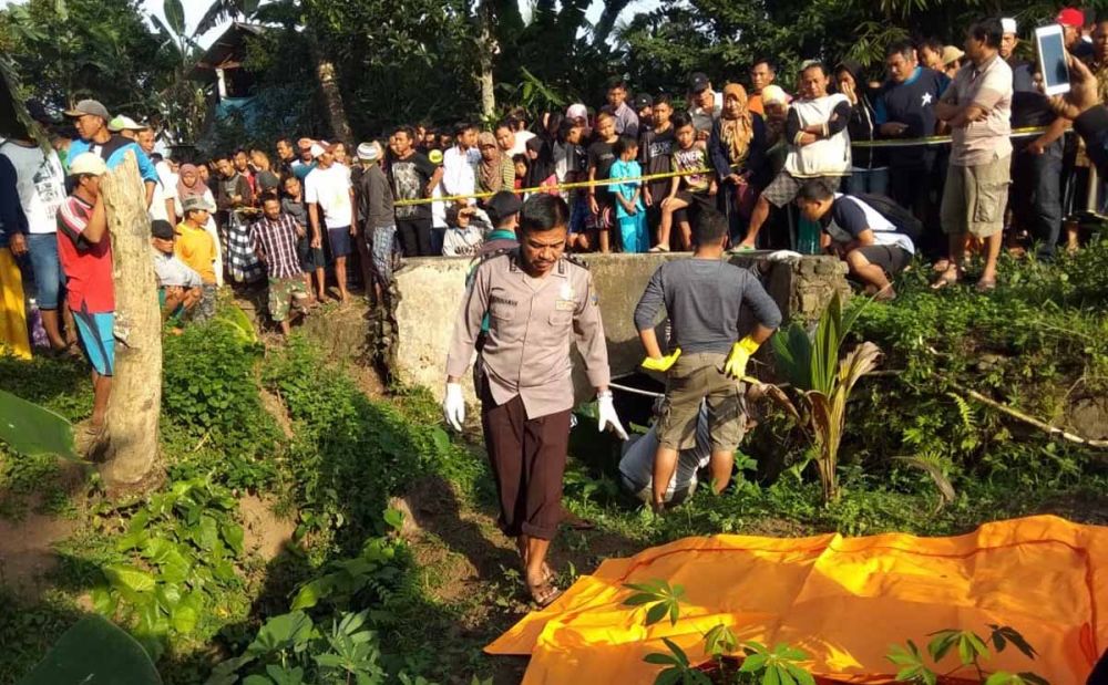 Petugas mengevakuasi mayat pria penuh luka yang ditemukan di areal persawahan di Banyuwangi