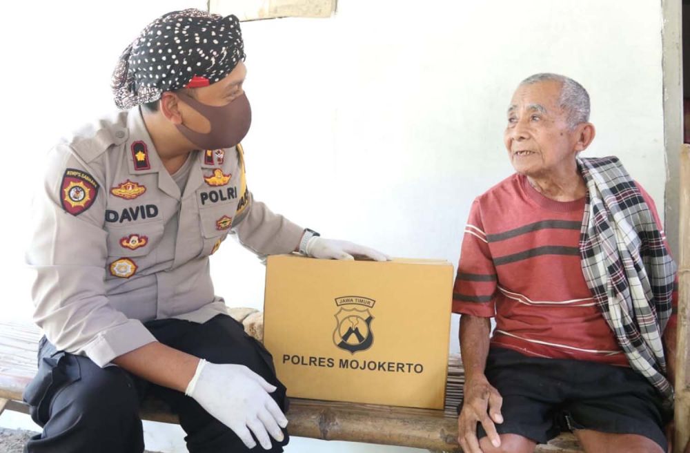 Wakapolres Mojokerto Kompol David Triyo Prasojo berbincang dengan salah satu warga yang menerima bantuan paket sembako
