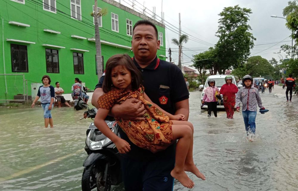 Seorang anggota Banser membantu pengendara motor yang terjebak banjir di Jalan Raya Benjeng-Balongpanggang, Gresik (Foto-foto: Sahlul Fahmi/jatimnow.com)
