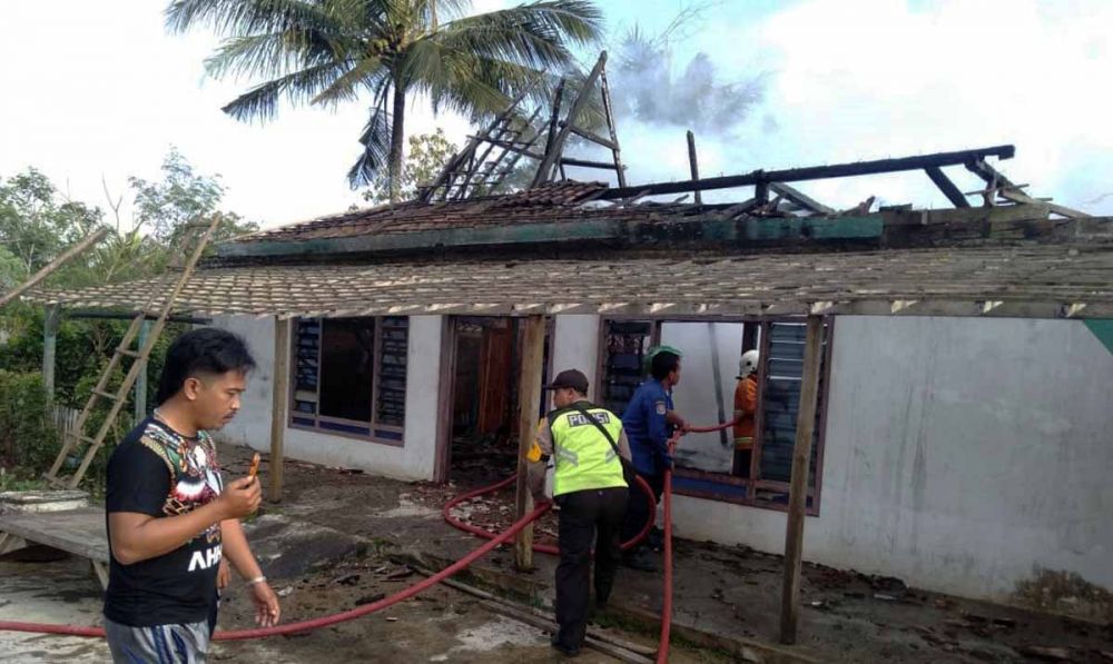 Petugas melakukan pembasahan di rumah yang terbakar di Blitar