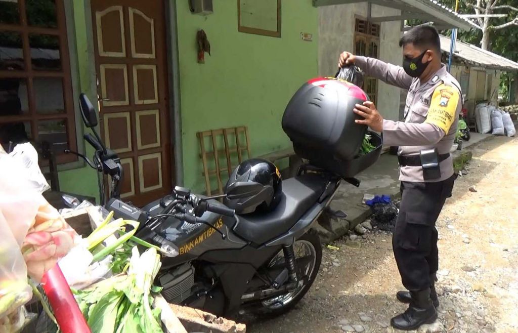 Bripka Rifain saat mengantarkan pesanan warga Pacitan yang sedang melakukan isolasi mandiri