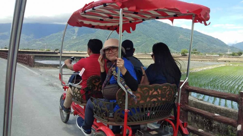 Wisatawan menikmati pemandangan alam pedesaan dengan sepeda roda empat