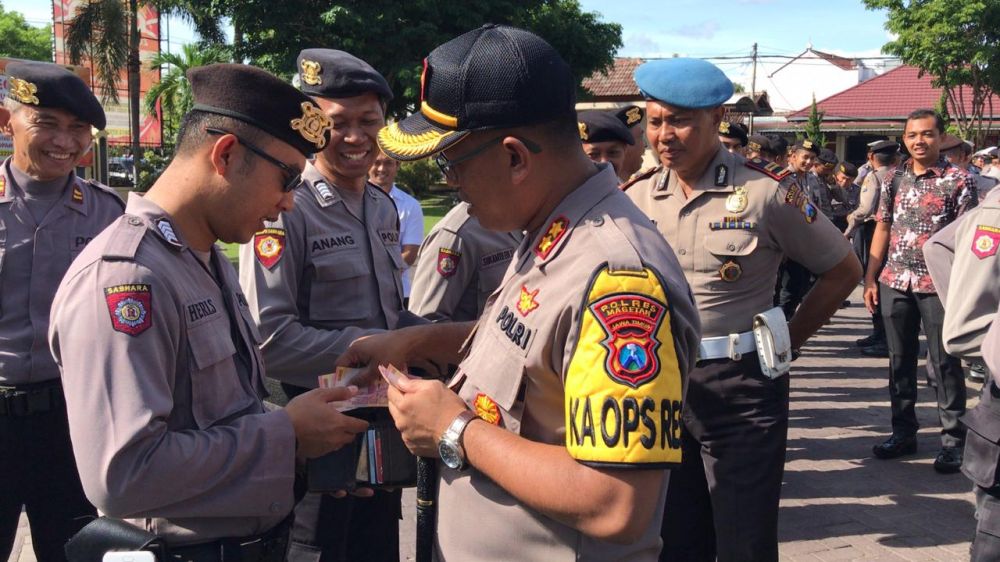 Kapolres Magetan AKBP Muhammad Rifai memberikan uangnya untuk dimasukkan ke dalam dompet anggotanya yang berisi sedikit uang